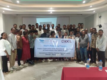 Ryhmä ihmisiä seisoo yhdessä huoneessa pitäen kylttiä terveydenhuollon koulutuksesta Amharassa.