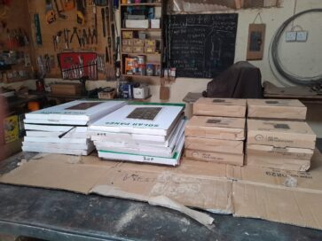 Paja, jossa on työkaluseinä, aurinkopaneelipaketteja ja LED-valaisimia pöydällä.