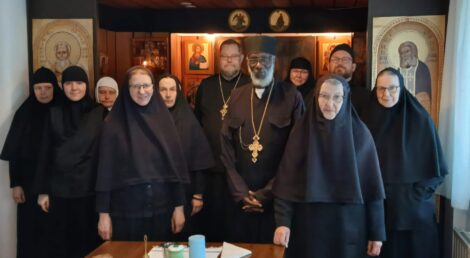 Ryhmä munkkeja ja nunnia ortodoksisessa kirkossa, taustalla ikoneja.