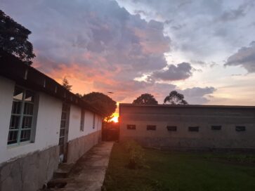 Auringonlasku näkyy kahden rakennuksen välistä, taustalla värikkäät pilvet.